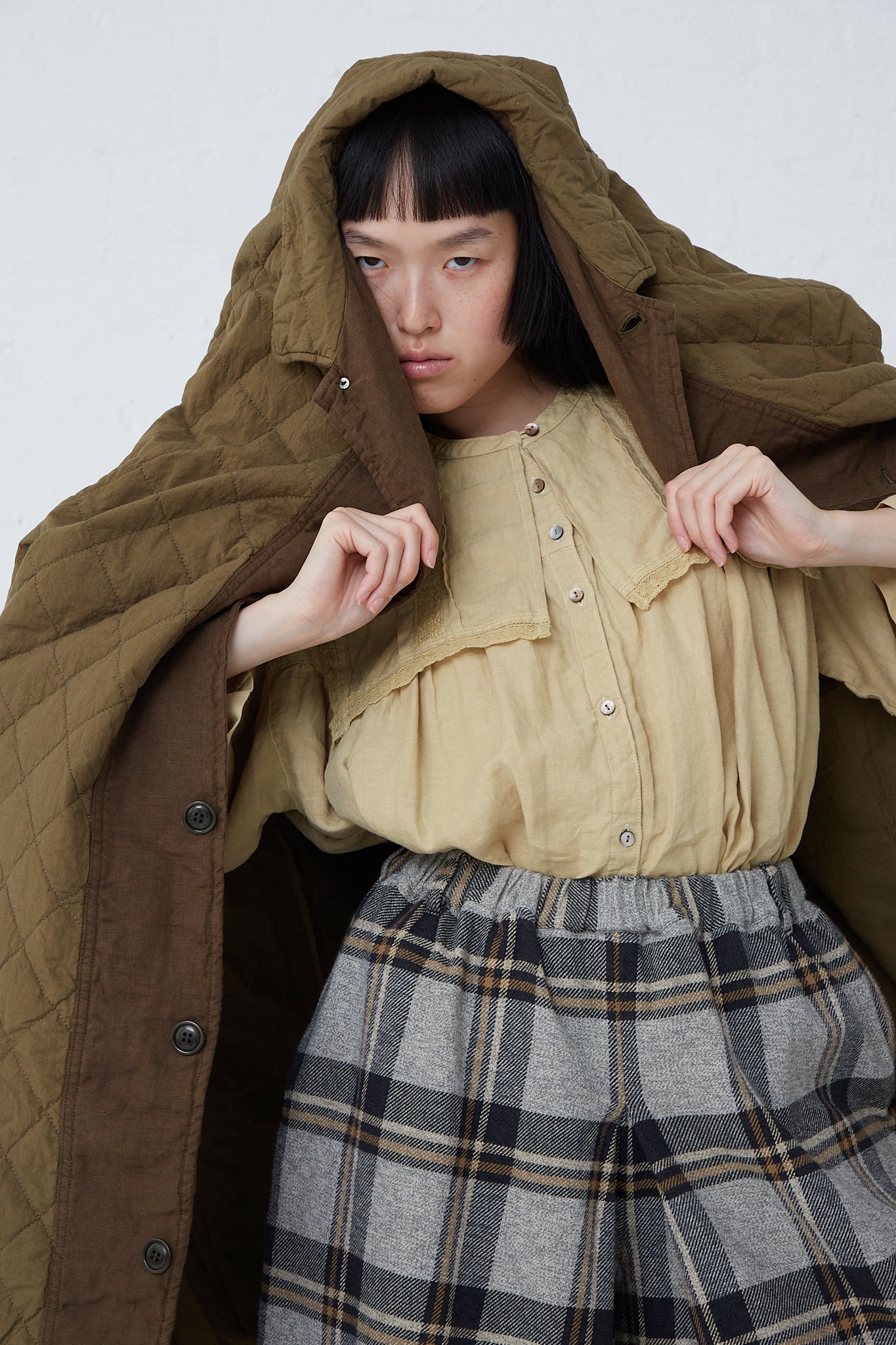 A woman in an oversized, nest Robe Cotton Ramie Quilted Long Coat in Olive.