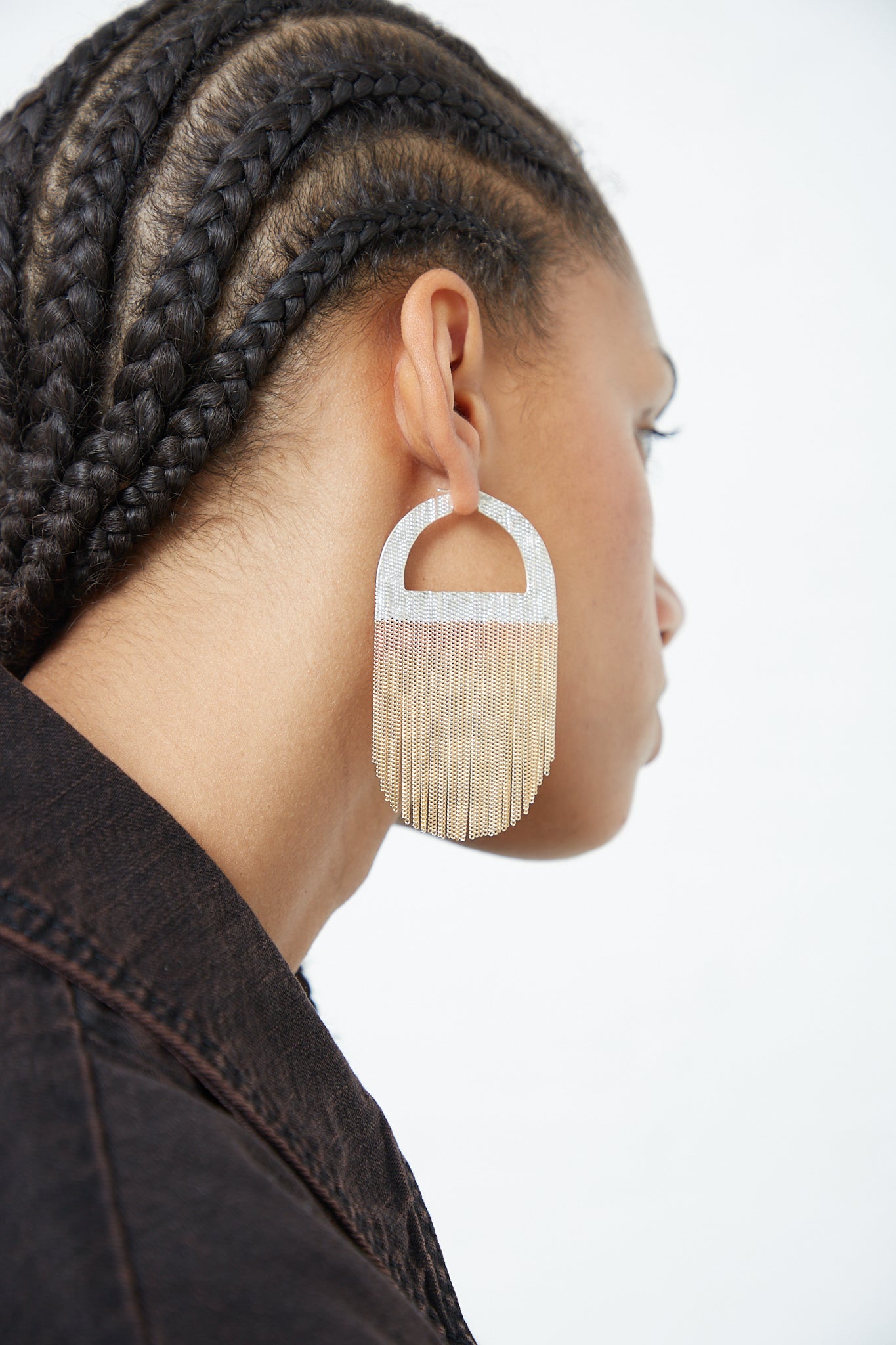 A woman wearing a pair of Hannah Keefe Sunrise Hoops in Brass Chain and Silver Solder fringe earrings.