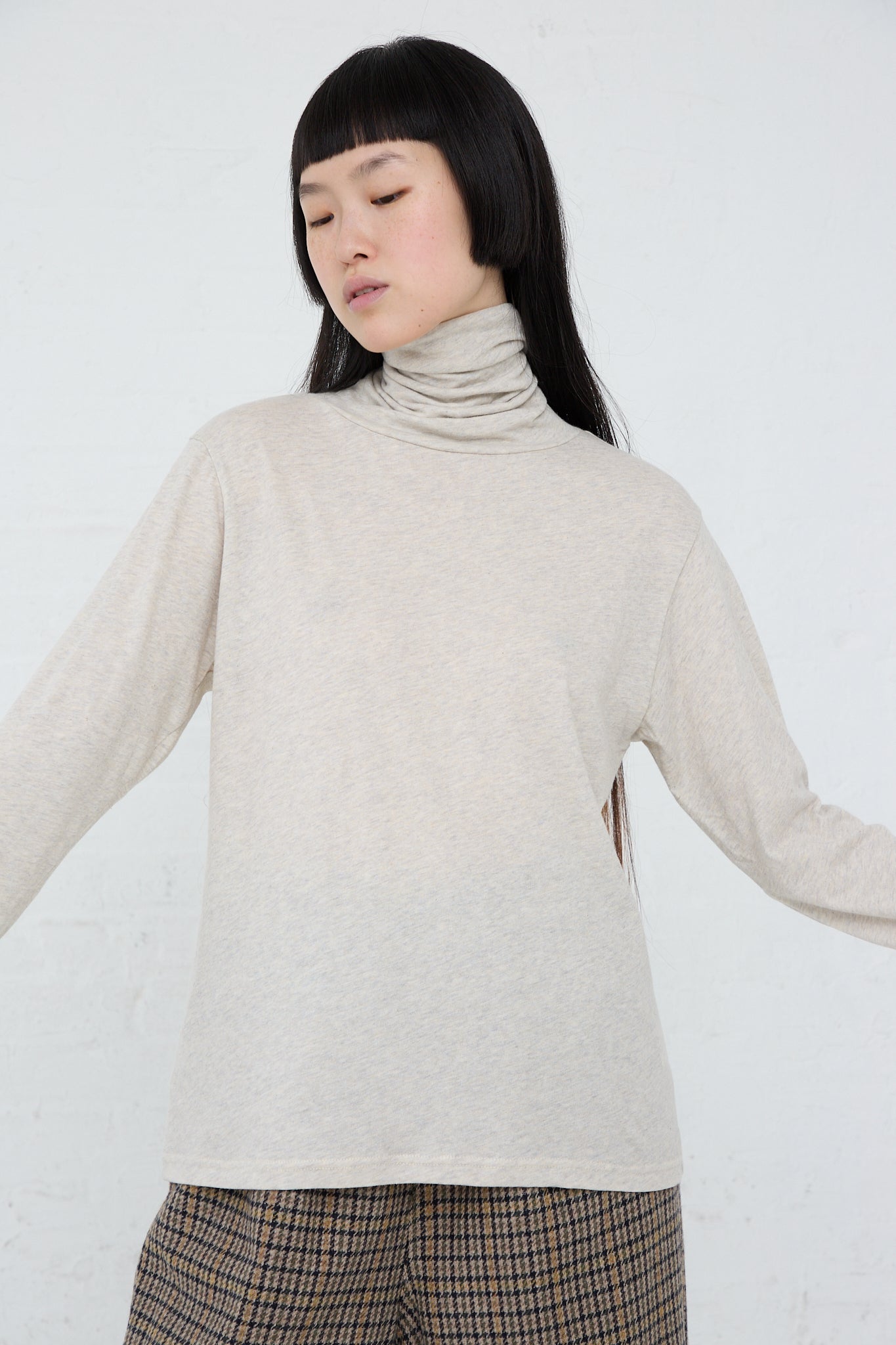 The model is wearing a long sleeve Cotton Knit Turtleneck in Oatmeal turtleneck by Ichi.