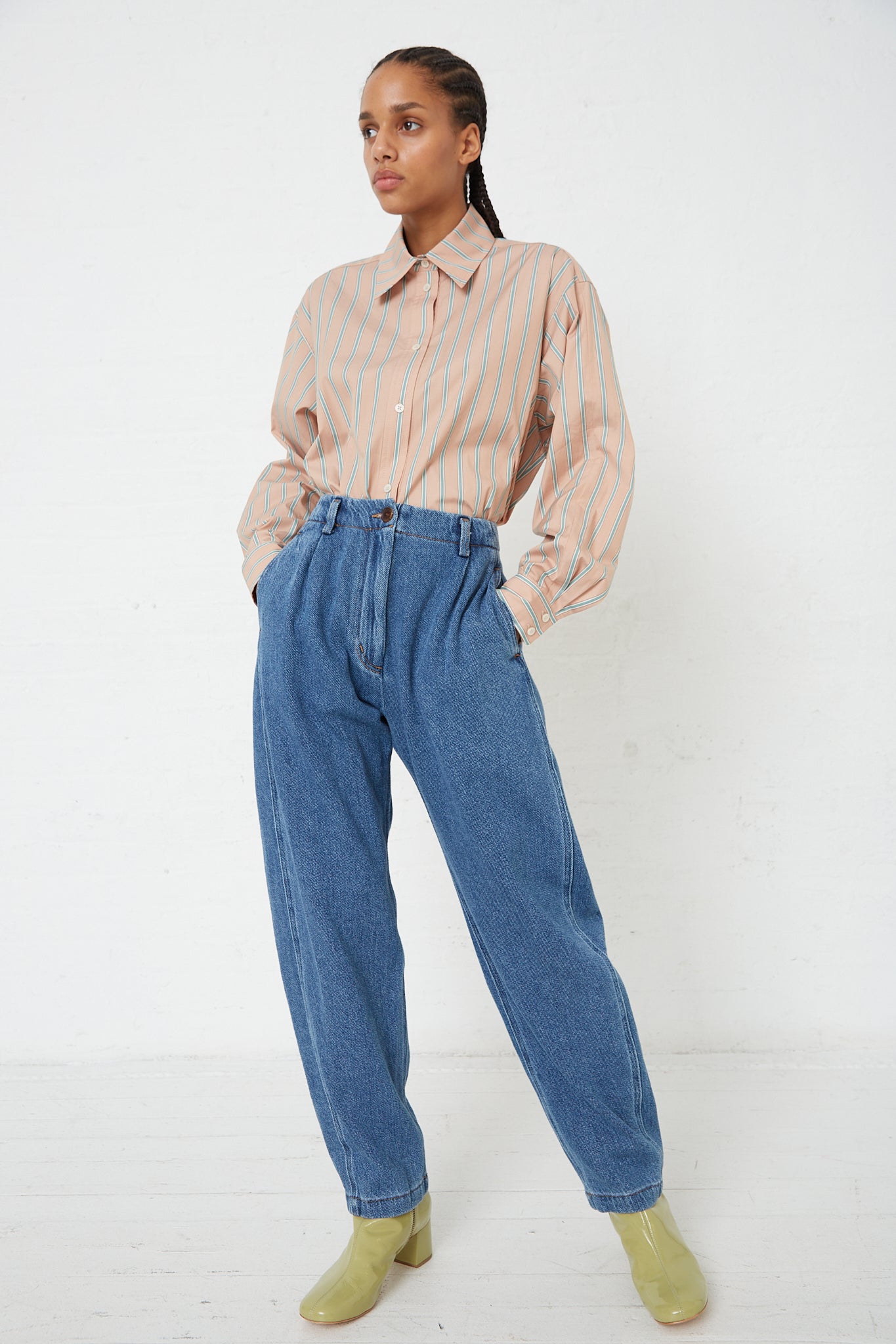 The model is wearing a striped shirt and washed Rachel Comey Denim Percy Pant in Indigo.