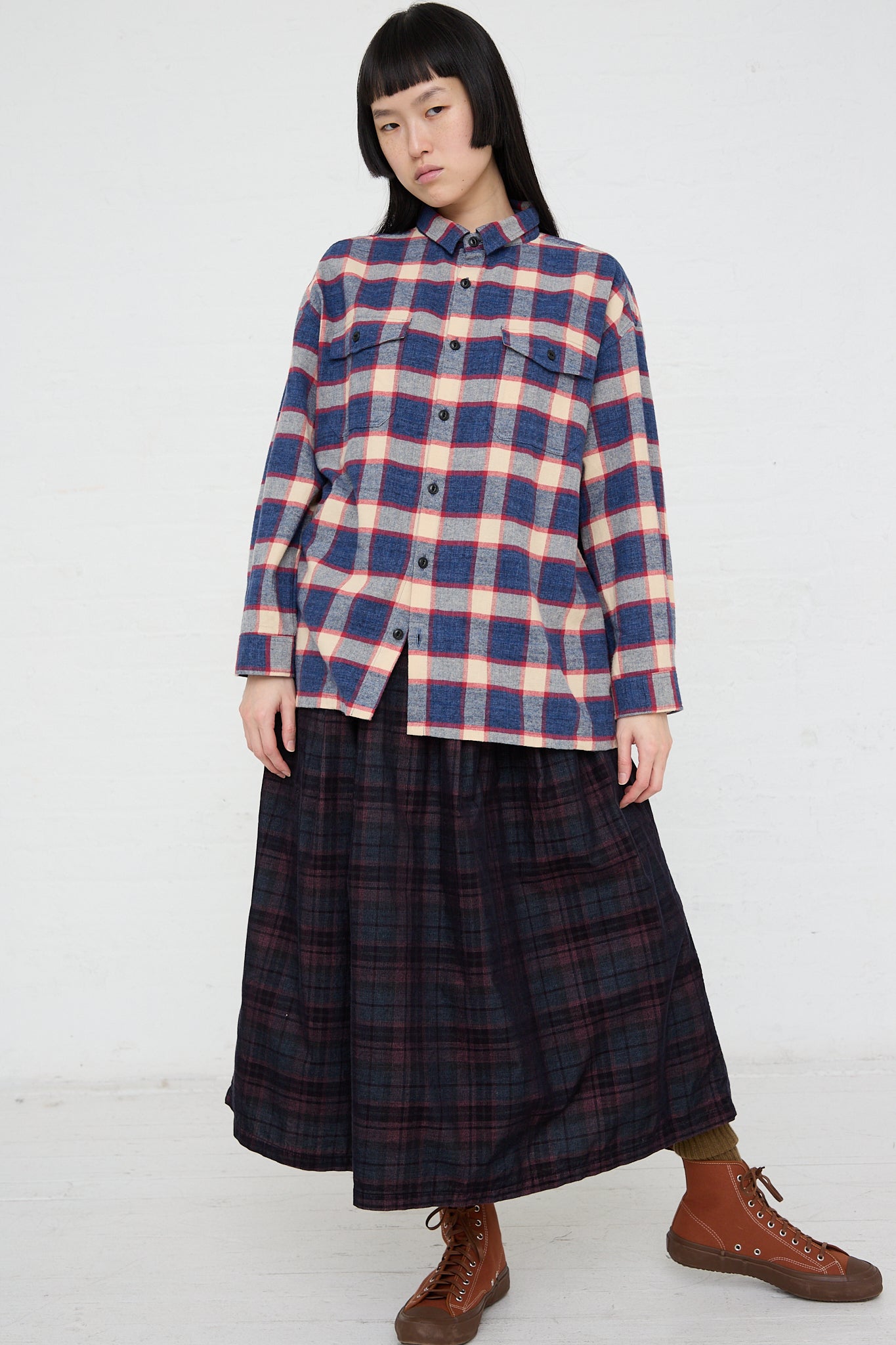 A woman wearing an Ichi plaid long sleeve woven cotton shirt in Ivory and Navy and skirt made of woven cotton.