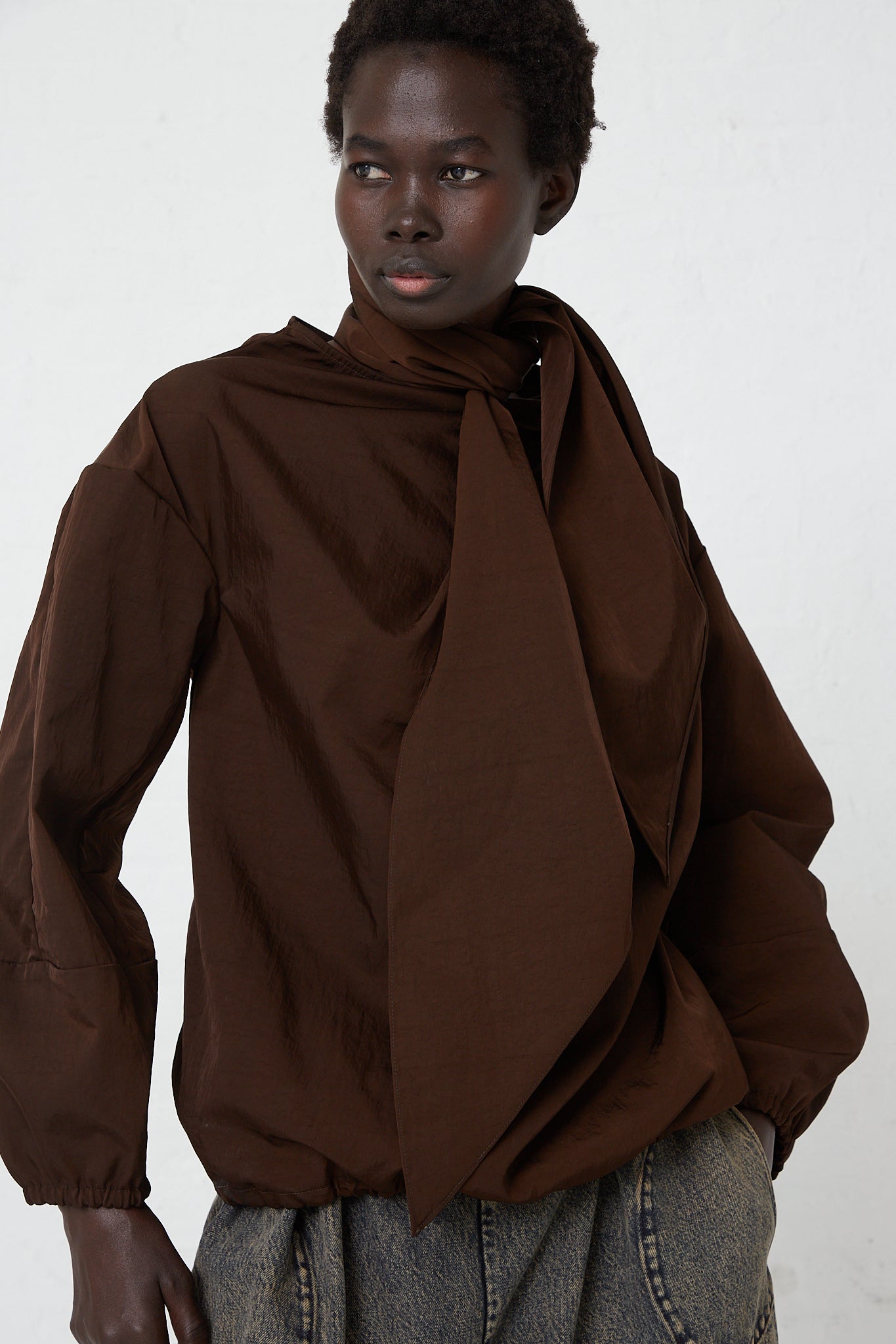 A woman wearing a Veronique Leroy Zipped on Sleeve Rain Blouse in Choco.