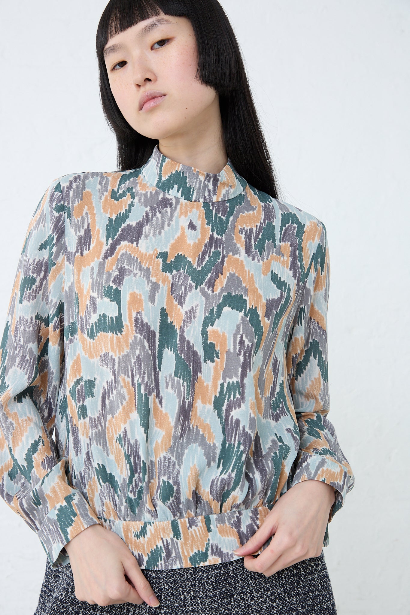 A model wearing the Mina Perhonen Light Dance Blouse in Gray Mix and camouflage print.