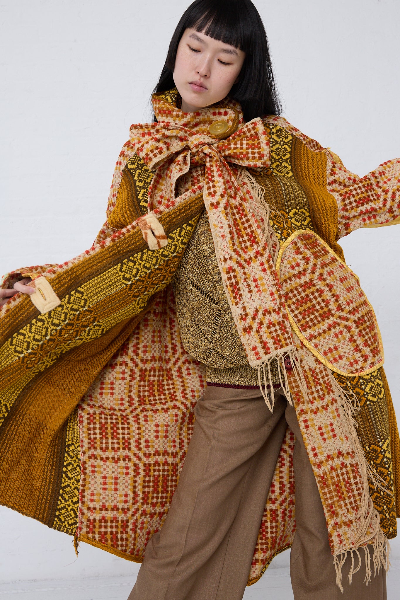 A woman wearing a Thank You Have A Good Day Patchwork Blanket Scarf Parka in Red, Yellow and Brown coat and pants. Front view. 