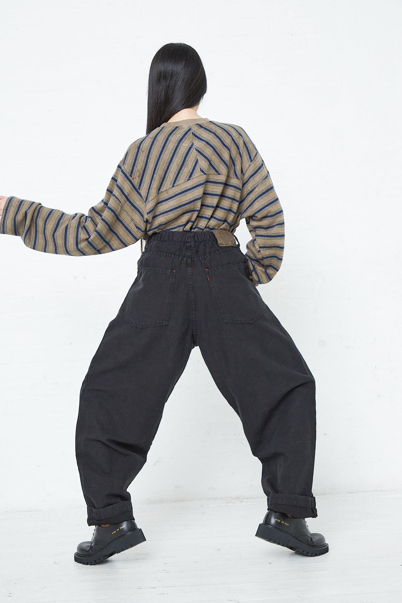A woman wearing the Dr. Collectors 9 oz. Cotton and Hemp P40 Z Boys Military Pant in Sulfur Black with a relaxed fit and an elasticated waistband, paired with a striped shirt.