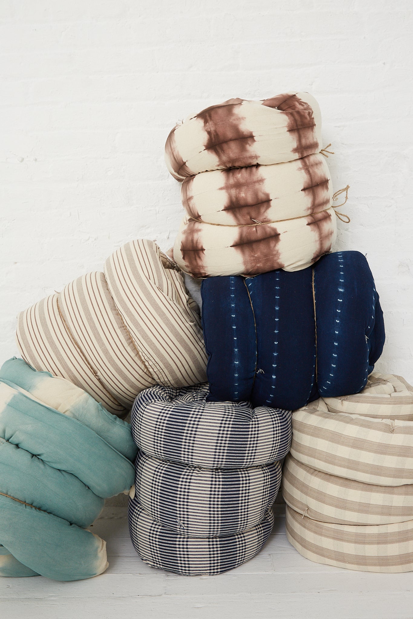 A stack of Tensira Tufted Overlay Mattresses in Dark Indigo Tie Dye piled up on top of each other.