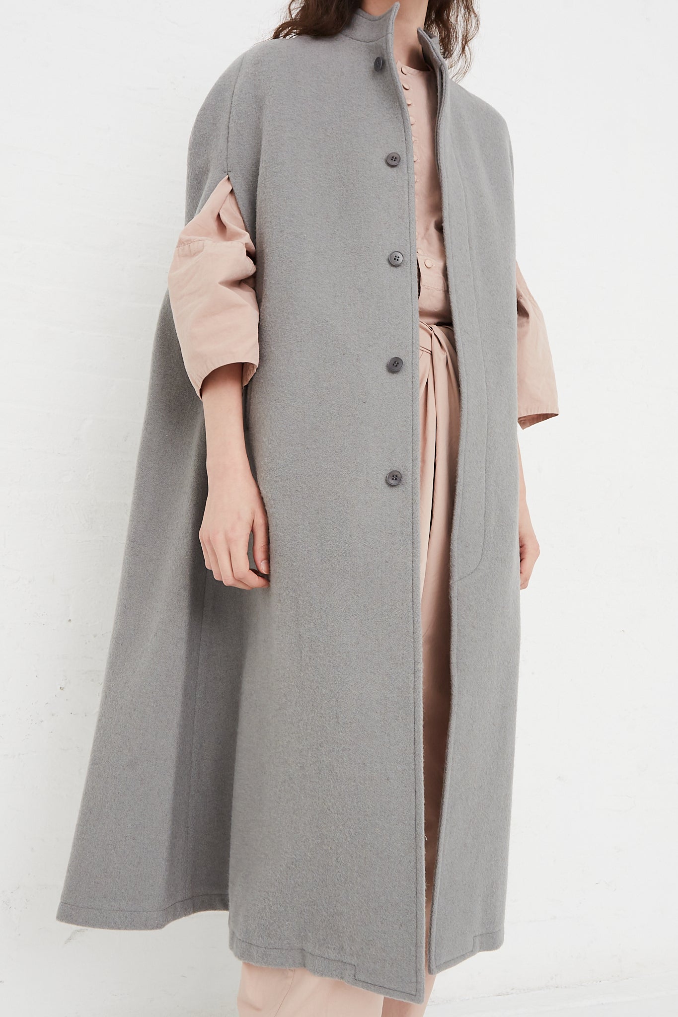 The model is wearing a Cosmic Wonder Japanese Suffolk Melton Cloak in Grey made of wool.