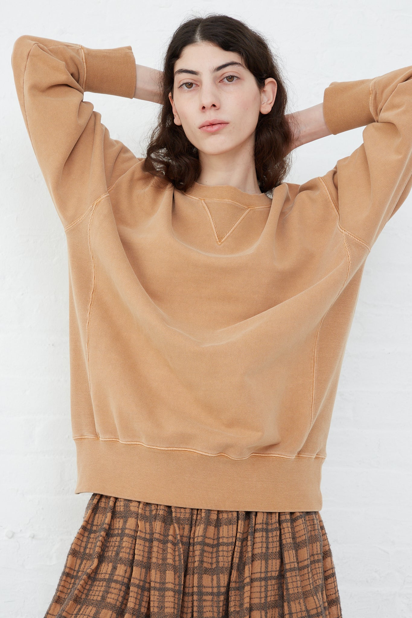 An oversized fit, crew neck Ichi Antiquités Pigment French Terry Cotton Pullover in Camel, paired with a plaid skirt.