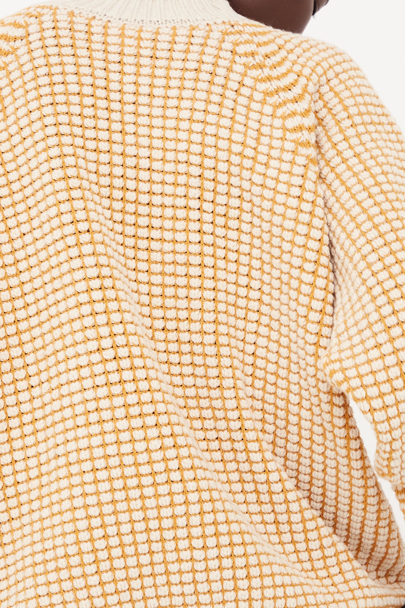 The back view of a woman wearing a yellow Lalin merino wool oversized sweater.