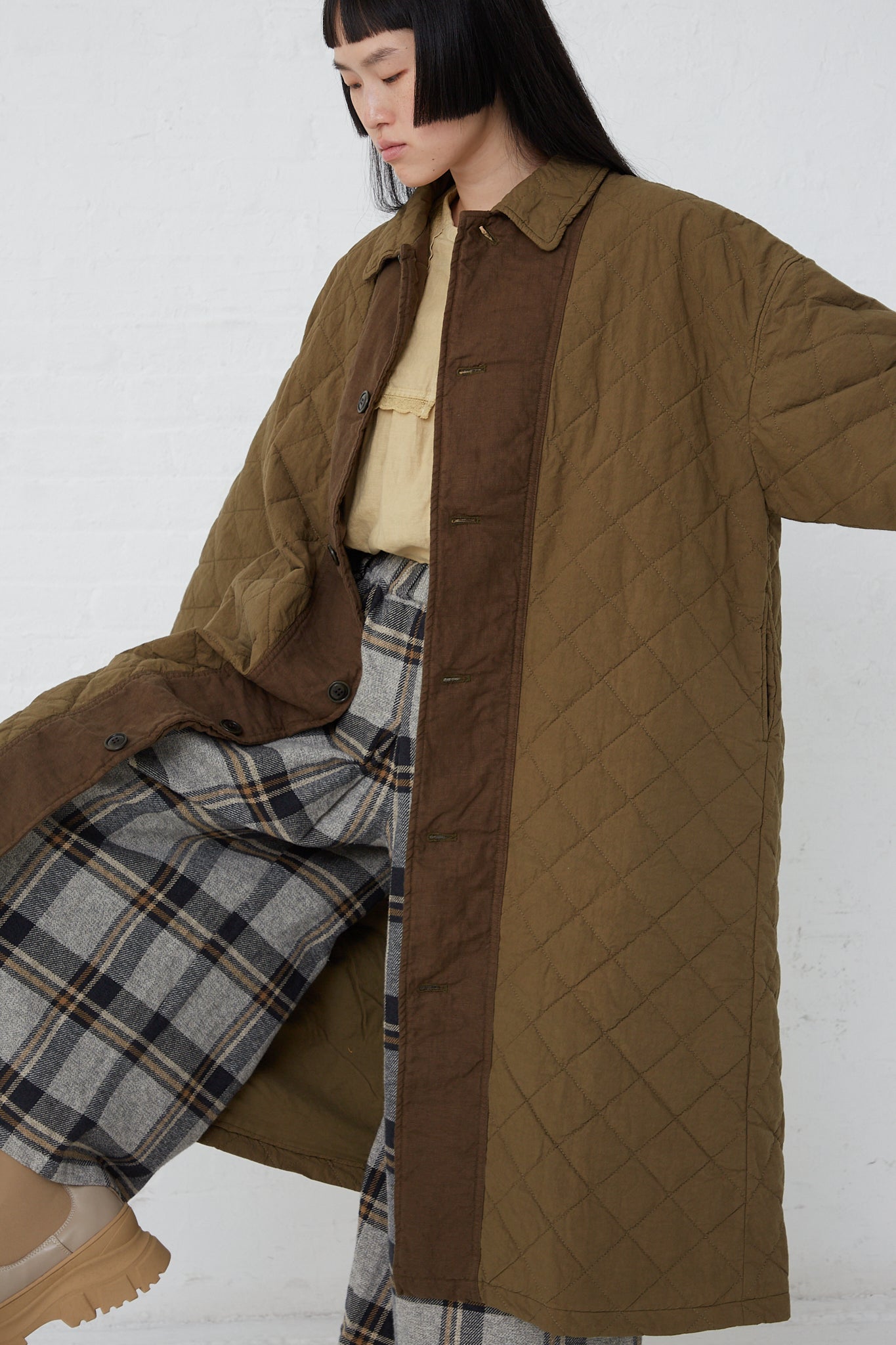 A woman wearing the "Cotton Ramie Quilted Long Coat in Olive" by nest Robe.