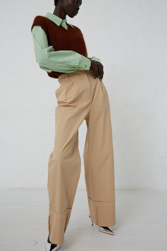 A woman wearing Rejina Pyo's Cotton Blend Macie Trouser in Tan and a green sweater.
