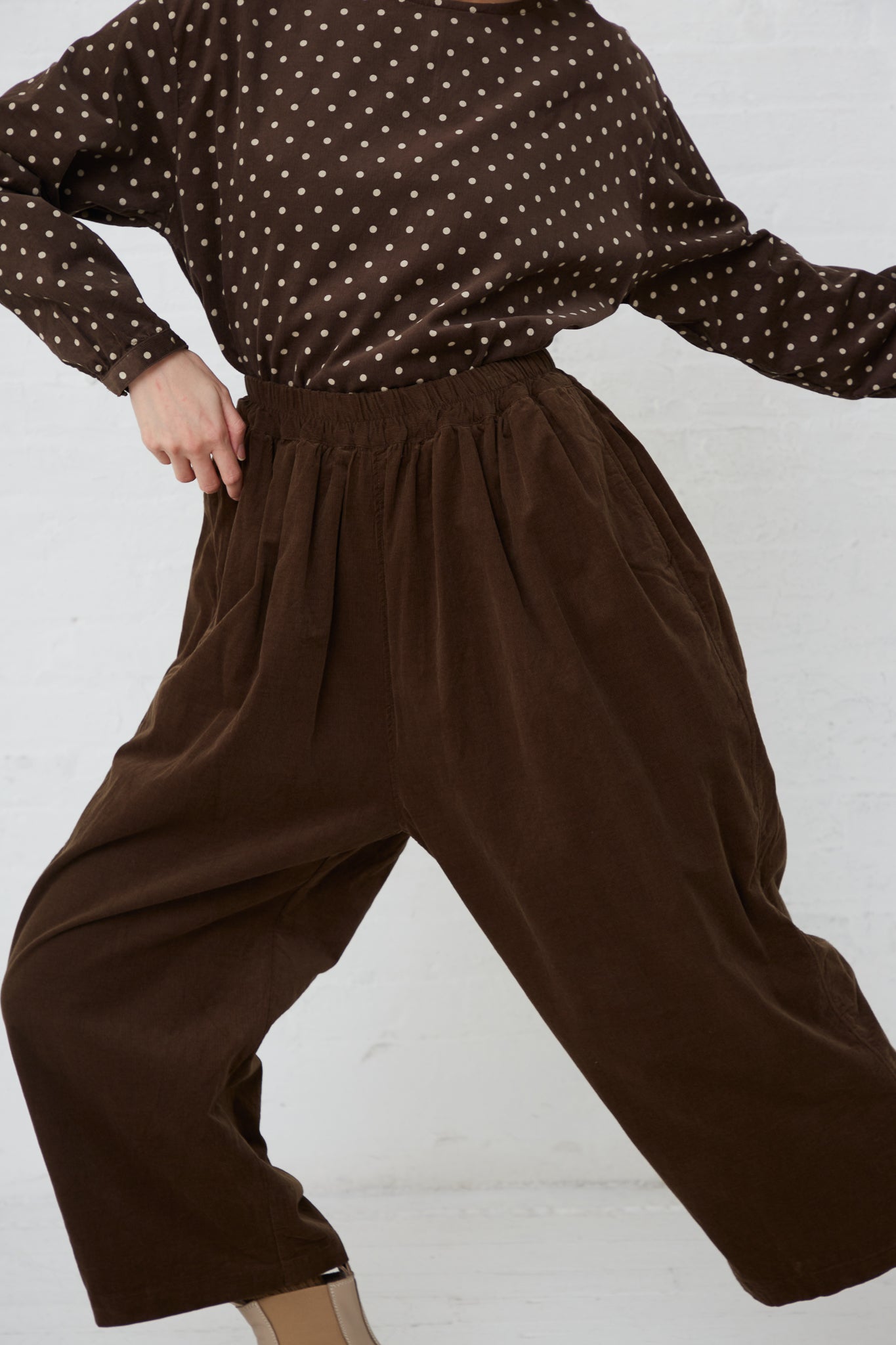 A woman wearing a relaxed fit Ichi polka dot top and brown pants.