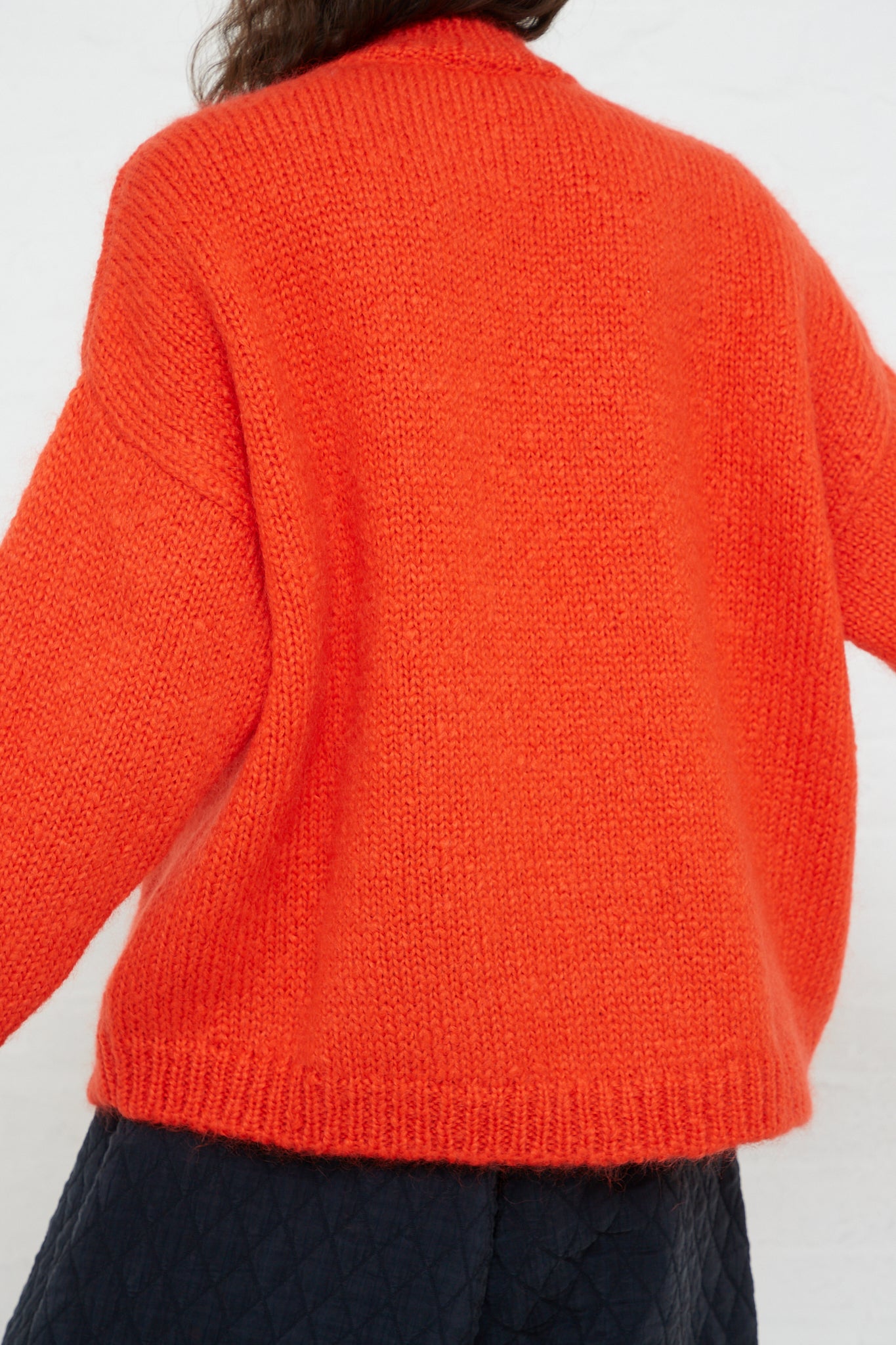 The back view of a woman wearing a Cordera Mohair Sweater in Tangerine.