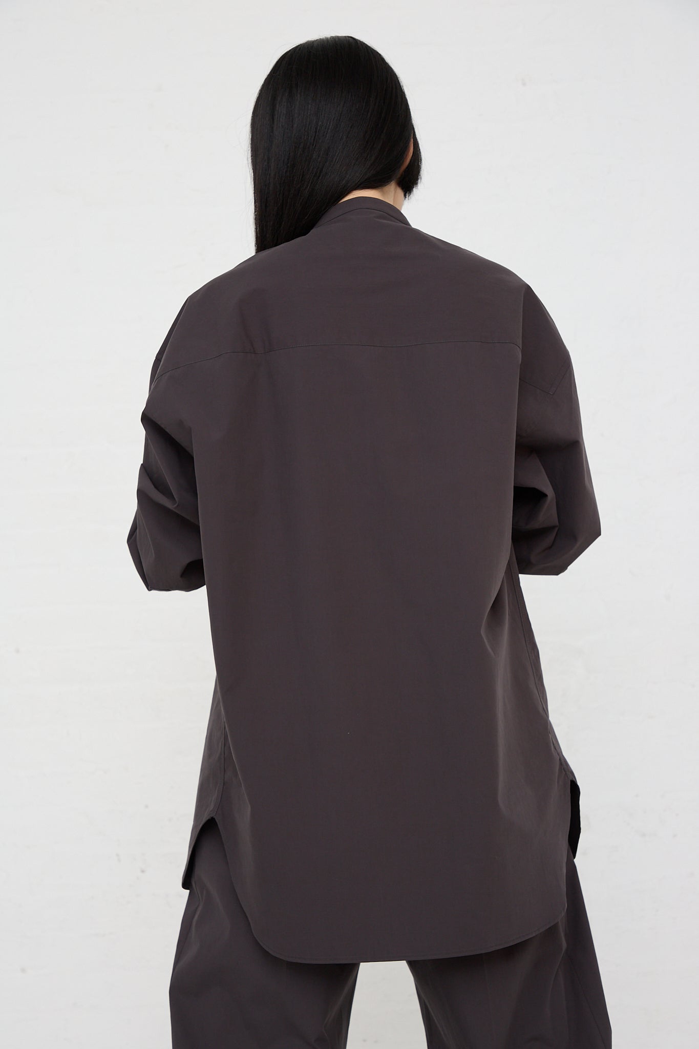 The back of a woman wearing a Studio Nicholson Frink Half Placket Shirt in Asphalt.