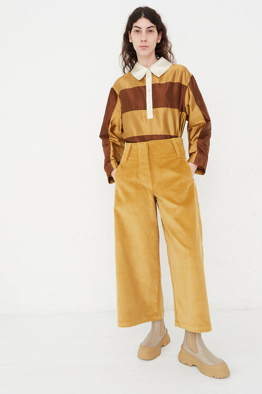 A model wearing a high waist trouser in a British cotton cord. Features a wide waistband, pleat detail and side welt pockets. Front view and full length. Designed by Cawley - Oroboro Store