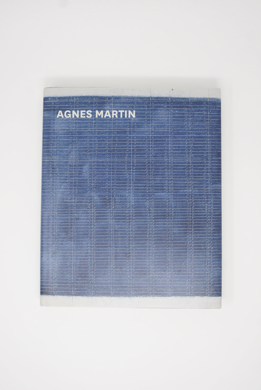 Artbook/D.A.P.'s Agnes Martin's retrospective exhibition of her artistic career, showcased in a book on a white surface.