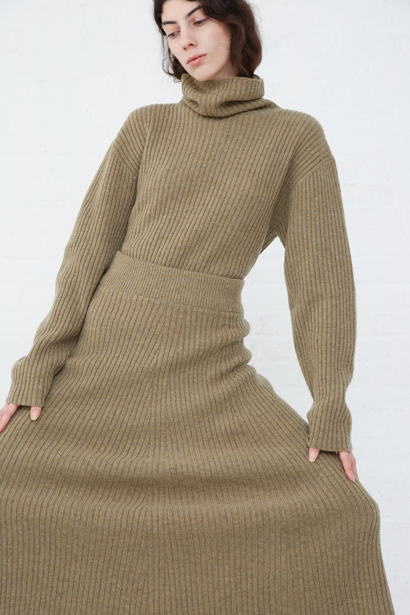 A woman wearing an Ichi Antiquités ribbed knit wool turtle neck sweater and midi skirt in mocha.