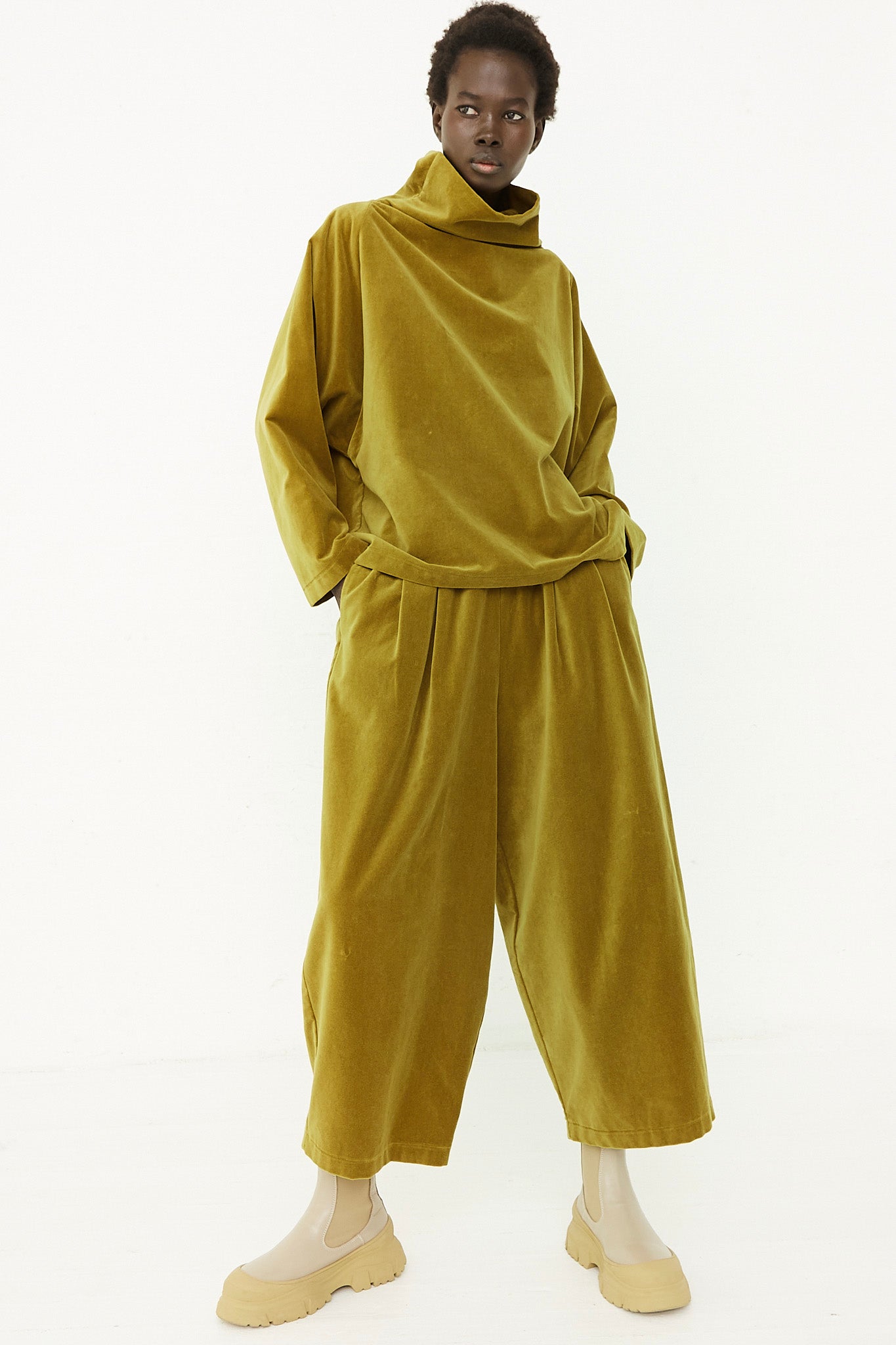 The model is wearing an olive cotton velveteen jumpsuit with an elasticated waist.