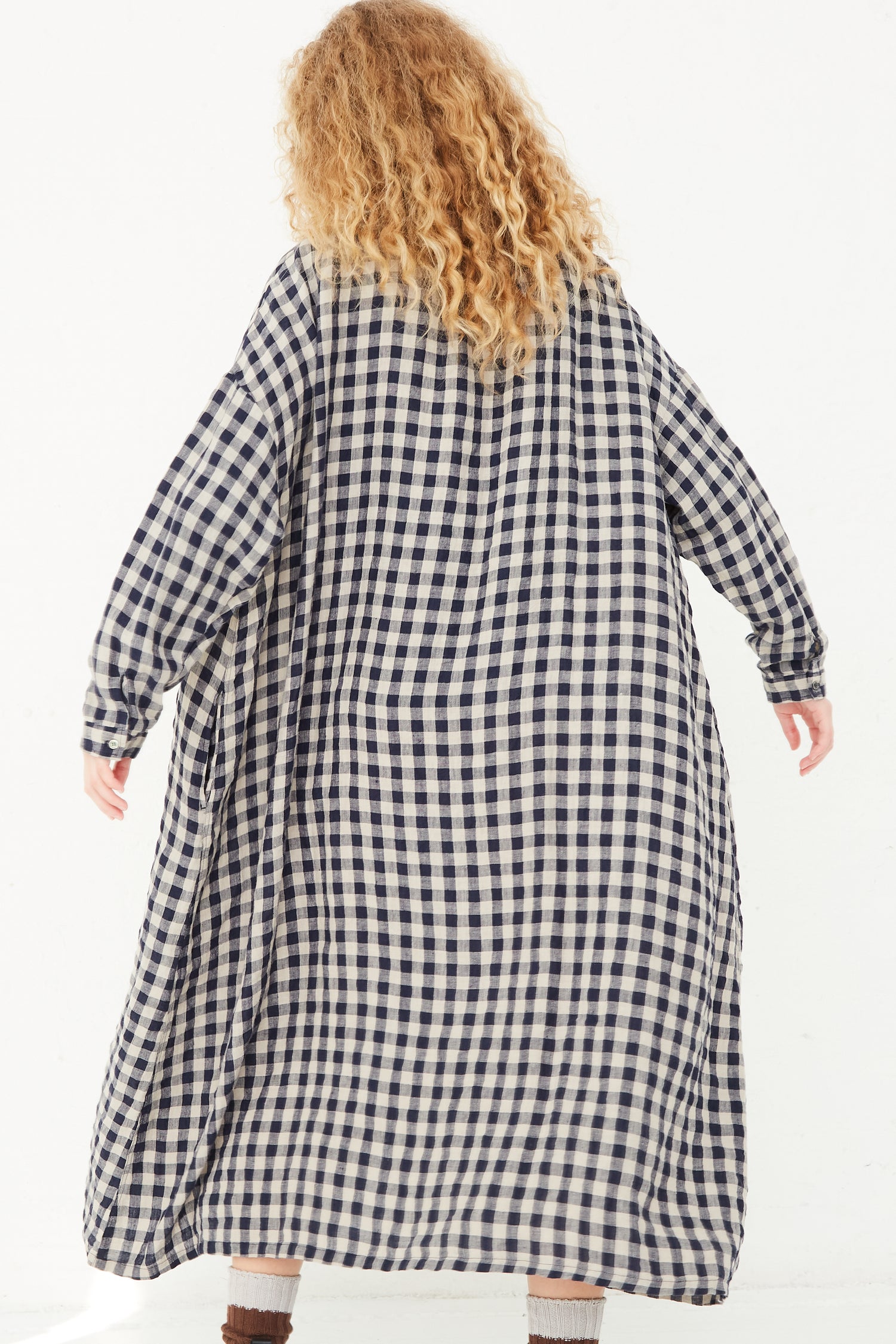 A woman wearing an Azumadaki Linen Gingham Dress in Beige by Ichi Antiquités, a relaxed fit, long sleeve dress in a blue and white checkered pattern.