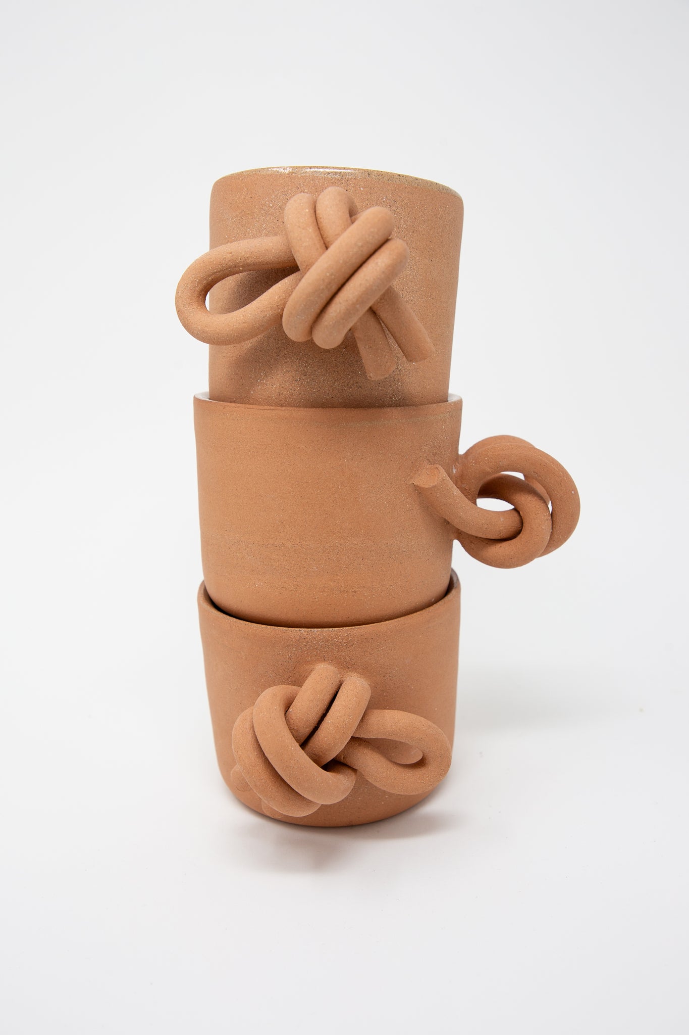 A stack of three Lost Quarry handmade clay pots with knots on them, made from terracotta.