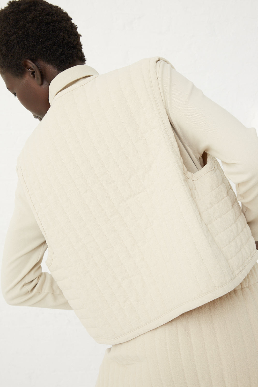 The back of a woman wearing a white quilted vest from Black Crane, an Los Angeles-based label.