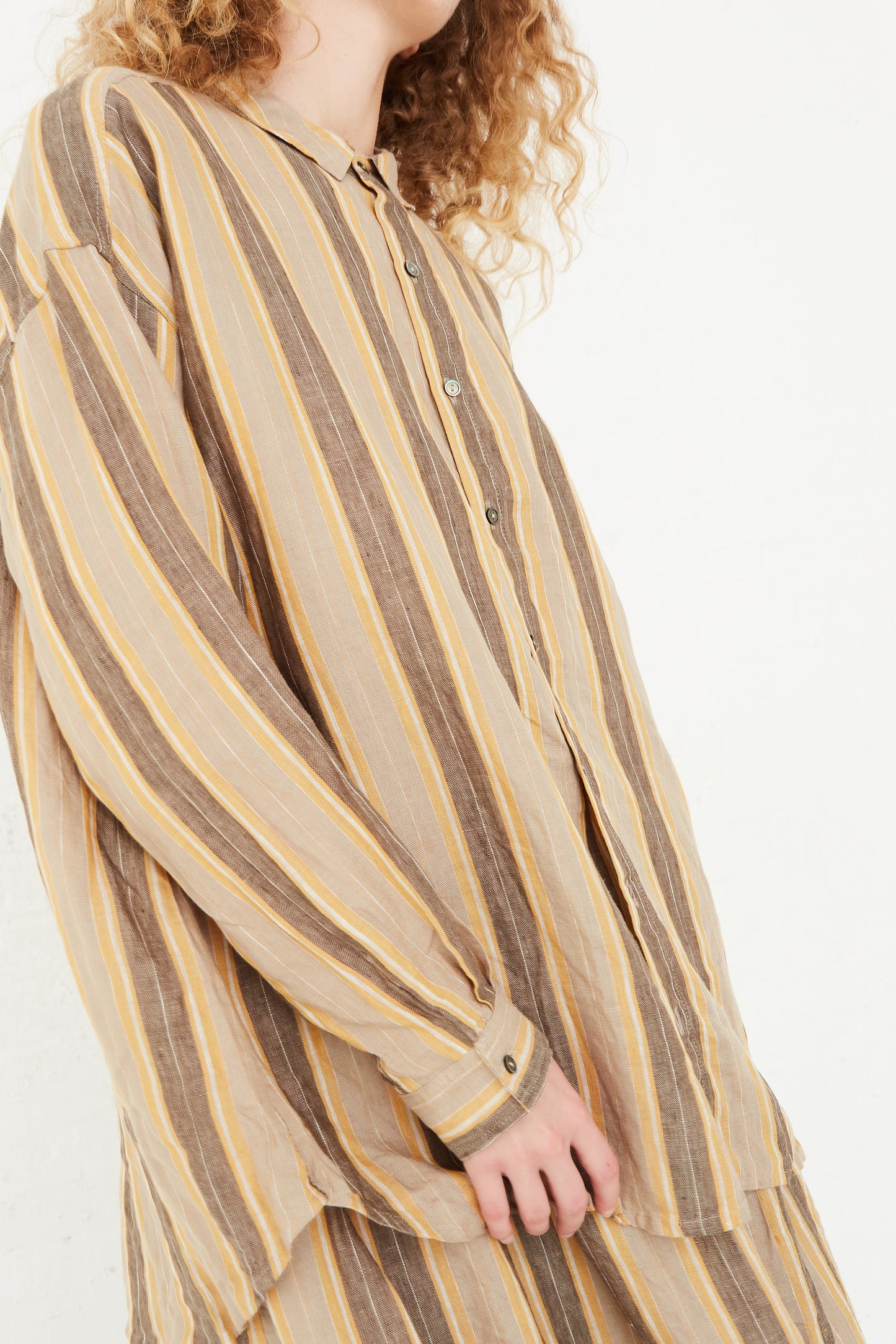 A model wearing a Linen Stripe Shirt in Mustard from Ichi Antiquités with curly hair.