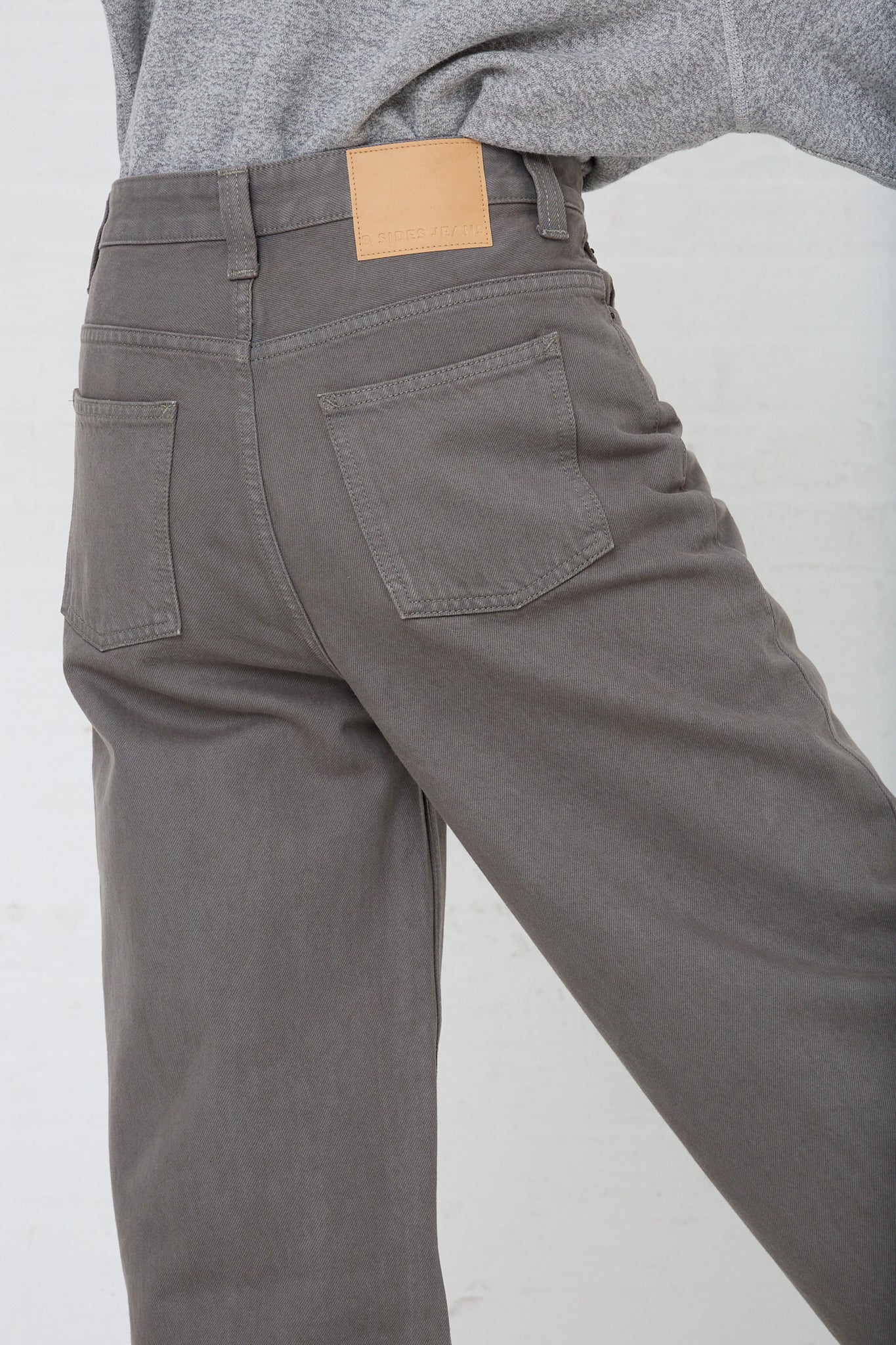 The back view of a model showcases B Sides Easy Mid Relaxed Jean in Olive Overdye with a tapered leg.