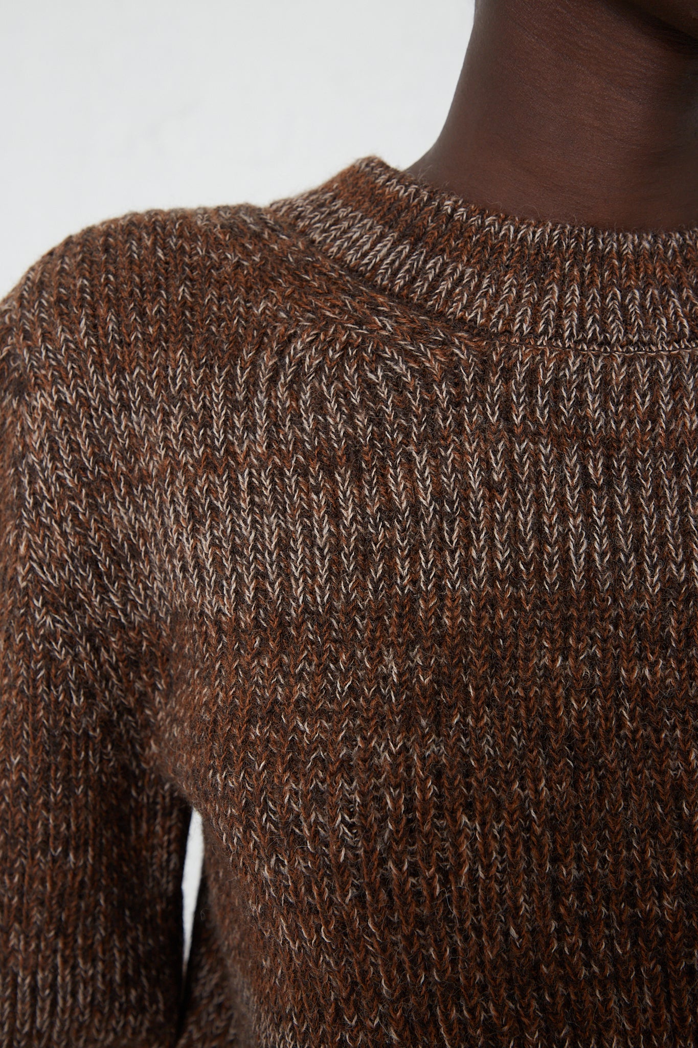 A close up of a woman wearing a Veronique Leroy Curved Sleeve Sweater in Oak.