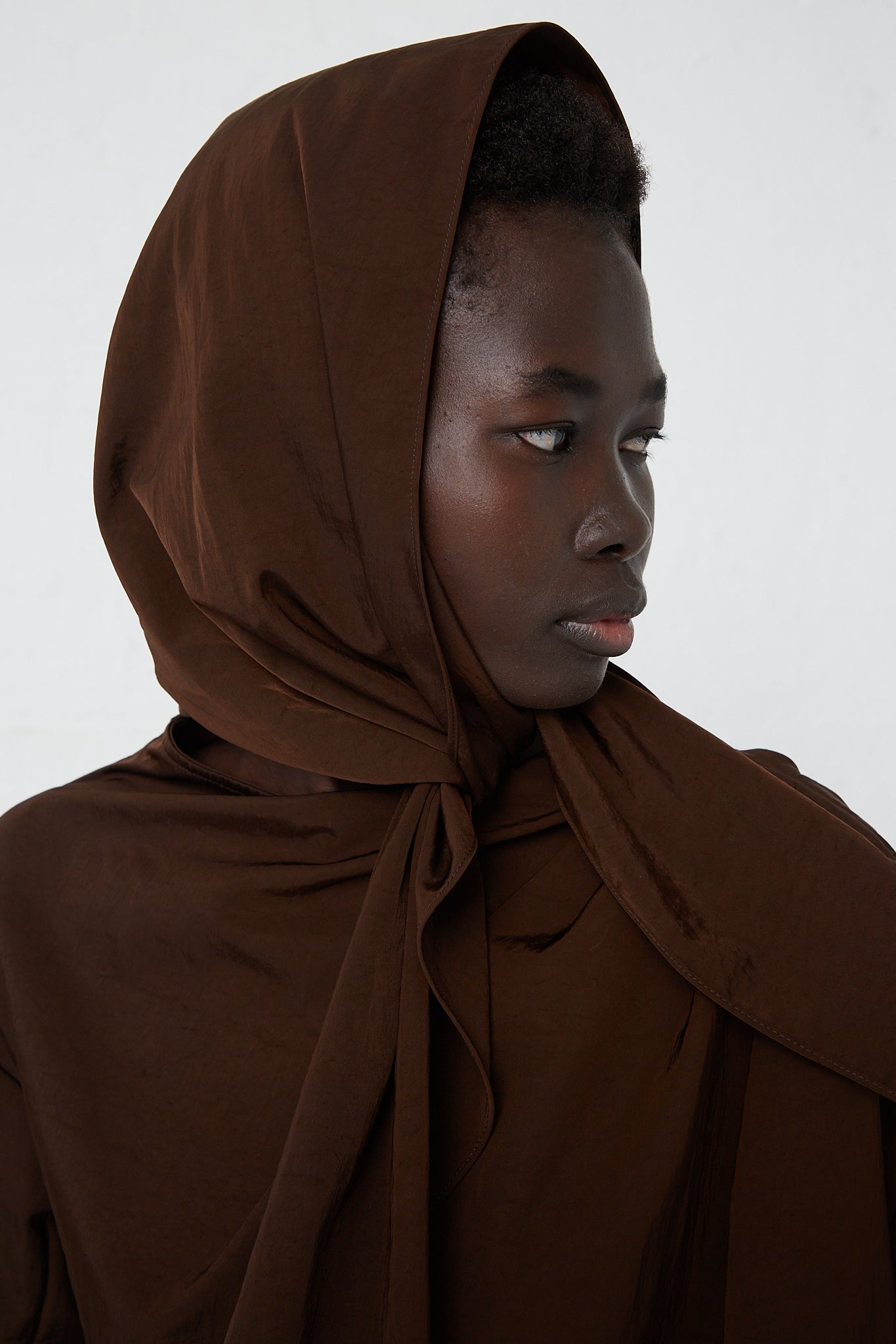A woman in a Veronique Leroy Zipped on Sleeve Rain Blouse in Choco with a removable hood.
