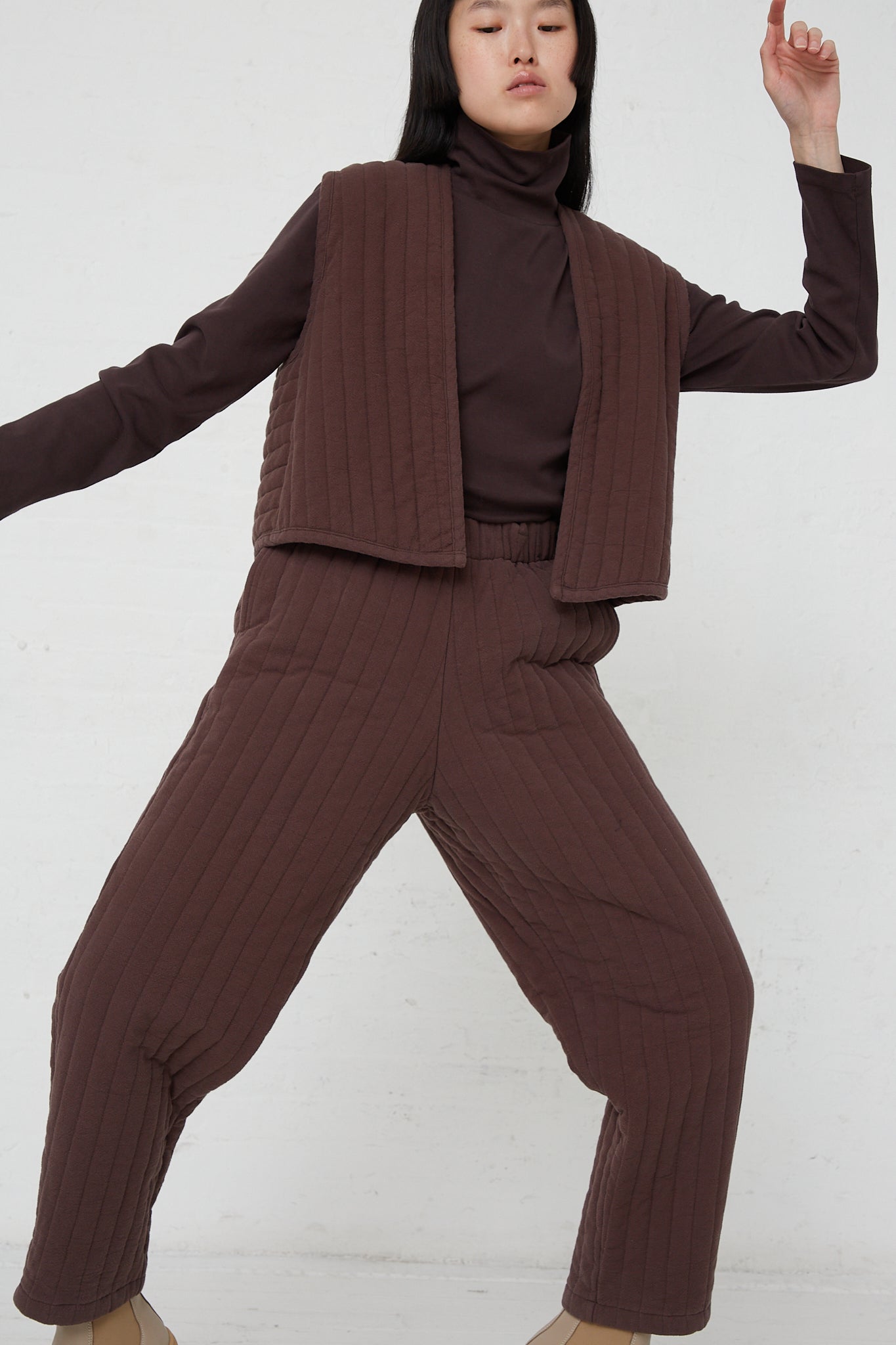 A model wearing a relaxed fit turtle neck sweater and Black Crane Quilted Easy Pants in Plum.