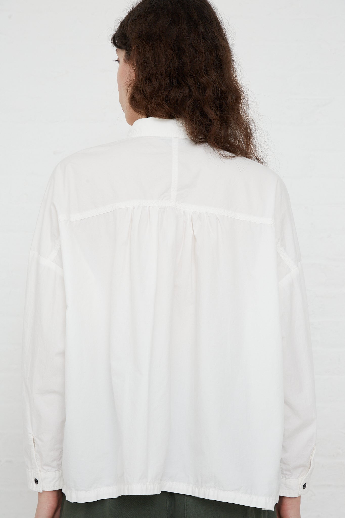 The back view of a woman wearing an Ichi Antiquités Woven Cotton Oumisarashi Shirt in White, made of natural fibers, specifically woven cotton.