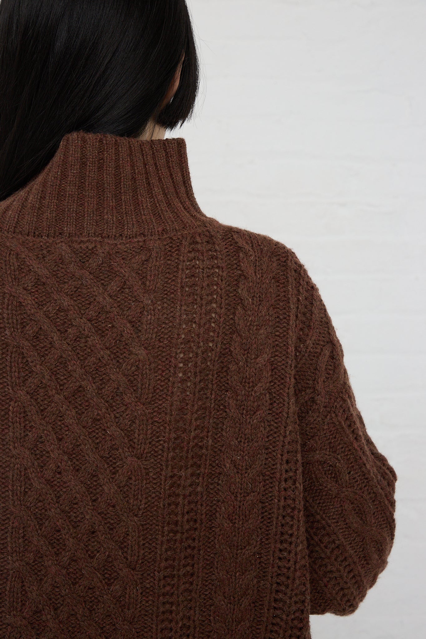 The relaxed fit, back view of a woman wearing an Ichi brown cable knit turtleneck pullover.