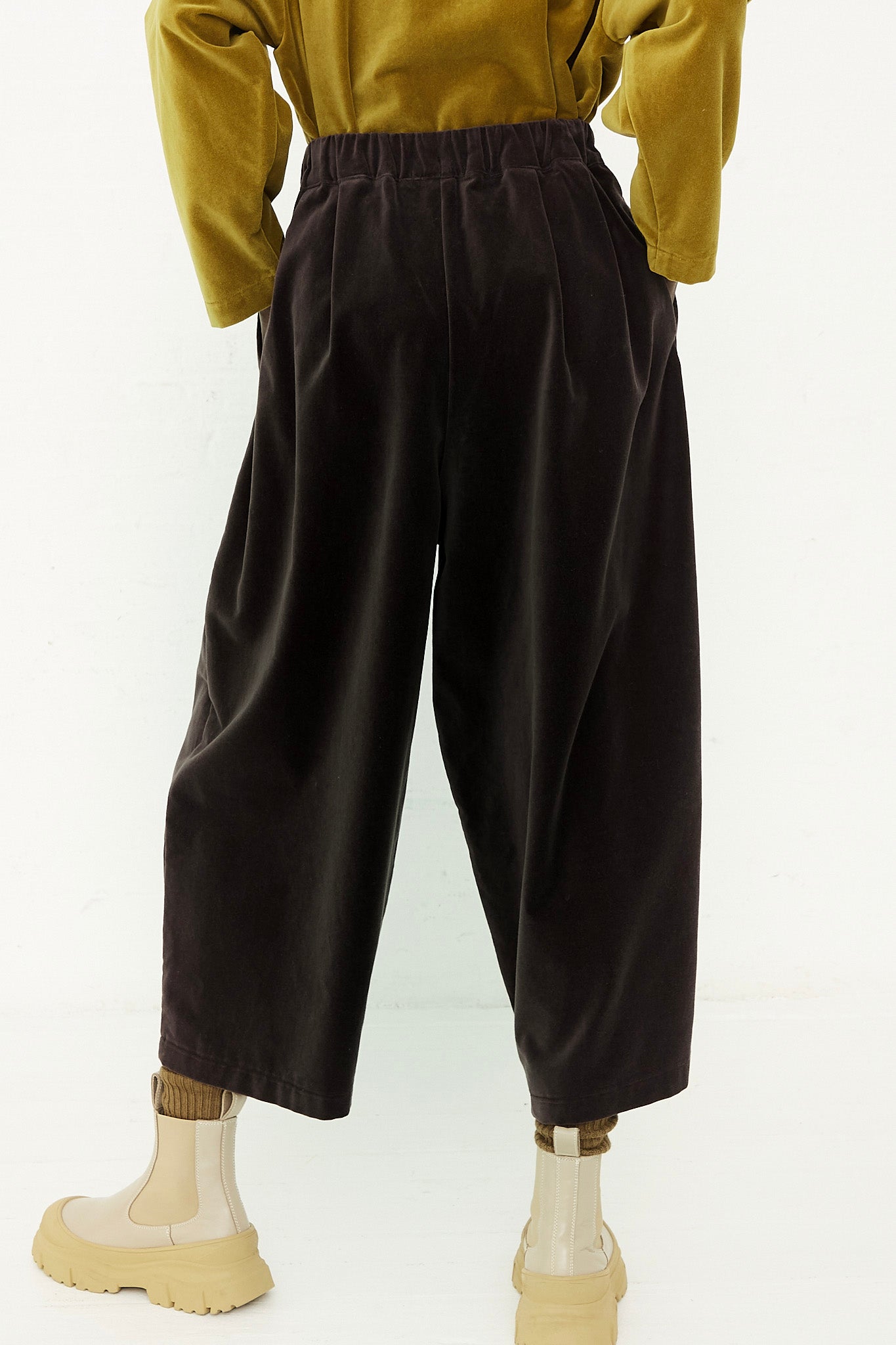 The back view of a woman wearing a yellow shirt and Black Crane Cotton Velveteen Wide Pants in Sumi Black with an elasticated waist.