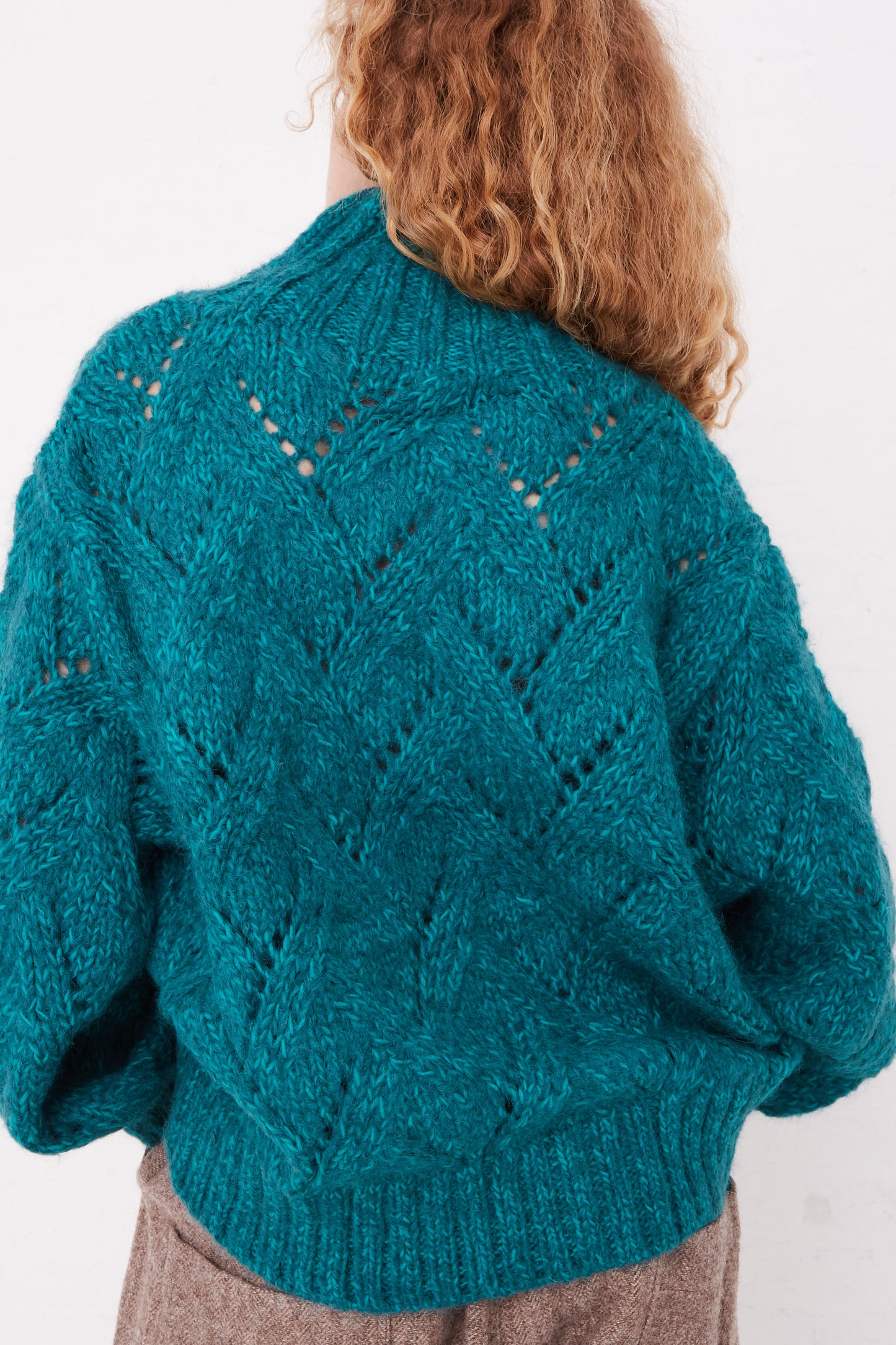 The back view of a woman wearing an oversized Ichi Antiquités Hand-Knit Turtleneck in Green Teal sweater.